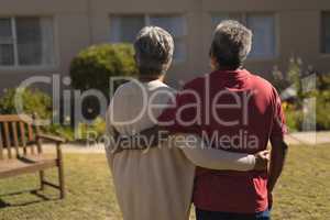 Senior couple standing with arm around in the park