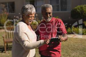 Senior couple using mobile phone in the park