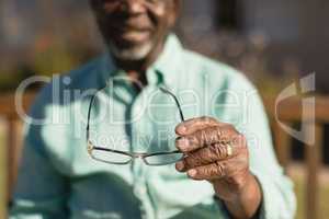 Senior man holding spectacle in the park of nursing home