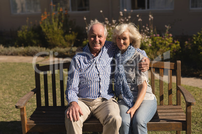 Senior couple sitting with arm around in the park