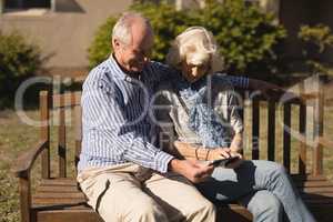 Senior couple using mobile phone in the park