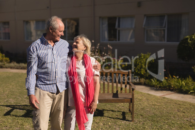 Senior couple standing with arm around in the park