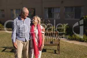 Senior couple standing with arm around in the park