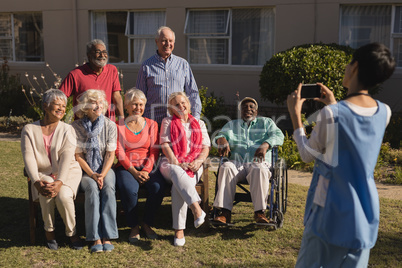 Woman clicking photo of senior people with mobile phone