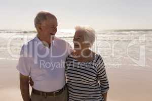 Senior couple with arms around looking each other on beach