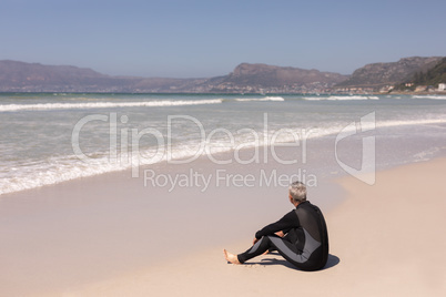 Rear view senior male surfer relaxing on the beach