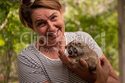 Woman holding slow loris smiles at camera