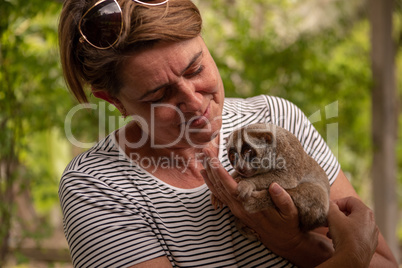 Woman looks at slow loris in hand