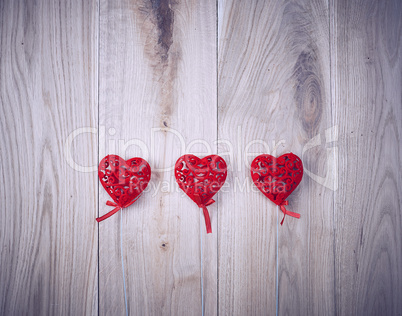 three red carved hearts on a stick