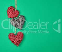 three wicker hearts hang on a rope, green background