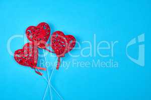 three red carved hearts on a stick on a blue background