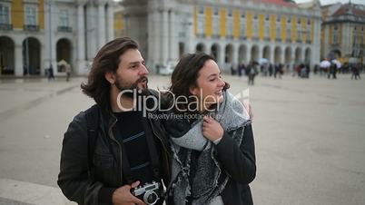 Bearded smiling man hugging girlfriend and pointing at distance