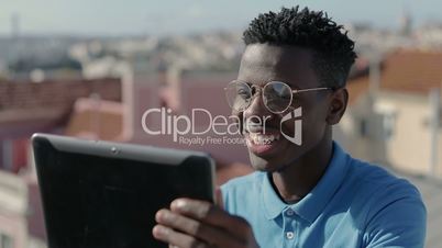 Cheerful smiling man greetings in video chat on digital tablet