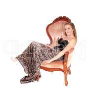 Lovely woman in a long dress lying in a armchair