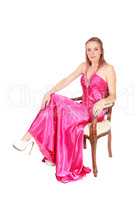 Beautiful woman sitting in a long pink evening dress