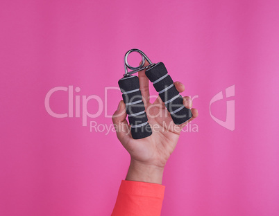 black espander in female hand on pink background