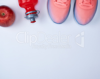 pink sports sneakers and a red water bottle