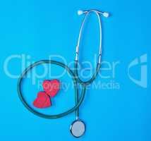 green medical stethoscope and two red wooden hearts