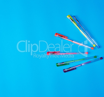 many multi-colored gel pens on a blue background