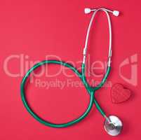 green medical stethoscope and wooden heart