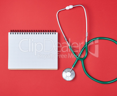 open blank notepad and green medical stethoscope