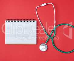 open blank notepad and green medical stethoscope