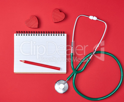 open blank notepad and green medical stethoscope