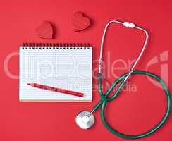 open blank notepad and green medical stethoscope