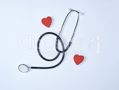 black medical stethoscope and two red wooden hearts
