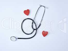 black medical stethoscope and two red wooden hearts