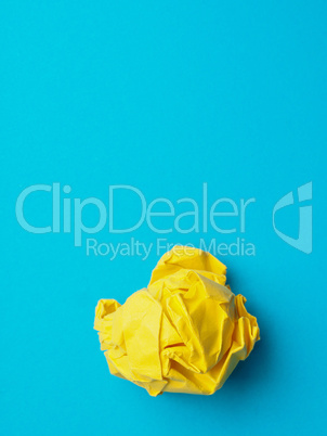Crumpled yellow paper ball on blue