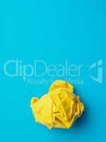 Crumpled yellow paper ball on blue