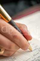 Hand with pen when signing document.