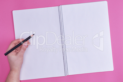 human hand holds black wooden pencil over empty open notebook