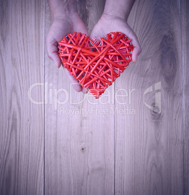 red heart in human hand on yellow wooden background