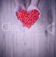 red heart in human hand on yellow wooden background