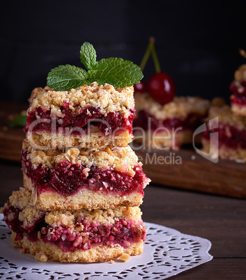 baked square pieces of cake with cherries