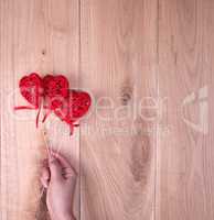 red hearts in human hand on yellow wooden background
