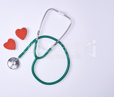 green medical stethoscope and two red decorative hearts