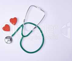 green medical stethoscope and two red decorative hearts