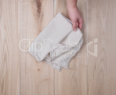 human hand is holding a folded gray kitchen towel