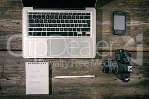 Office workstation with laptop, smartphone, camera, notebook and