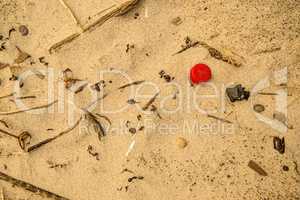 plastic waste on a beach, red lid