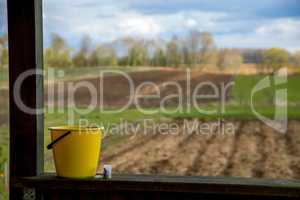 Yellow bucket next to the plowed field.