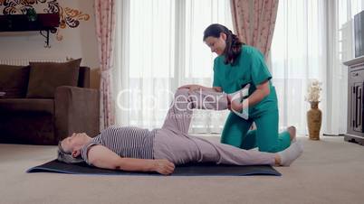 Young therapist exercising with older female patient in nursing home