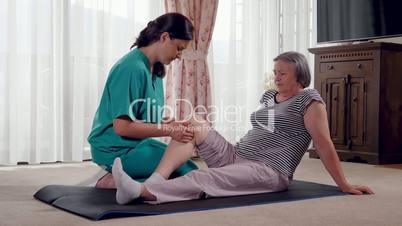 Young therapist exercising with older female patient