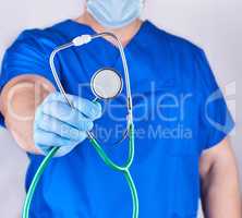 doctor in blue uniform and latex gloves holding a stethoscope