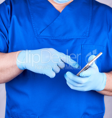 doctor in blue uniform and latex gloves holds a mobile phone