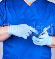 doctor in blue uniform and latex gloves holds a mobile phone