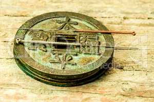 acupuncture needles on antique Chinese coin